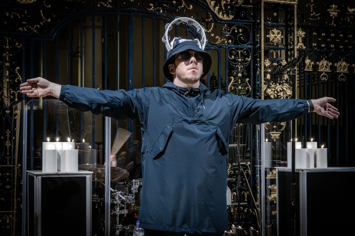 Oasis tribute band performing by candlelight at derby cathedral showing the lead singer with a tambourin on his head and his arms spread wide