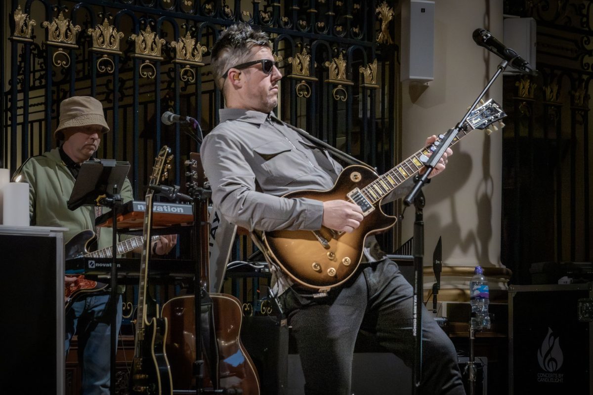 The lead guitarist of the Oasis tribute band performing by candlelight at derby cathedral