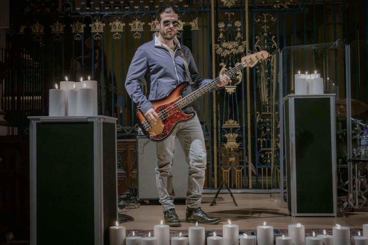 The bass guitarist of the Oasis tribute band performing by candlelight at derby cathedral
