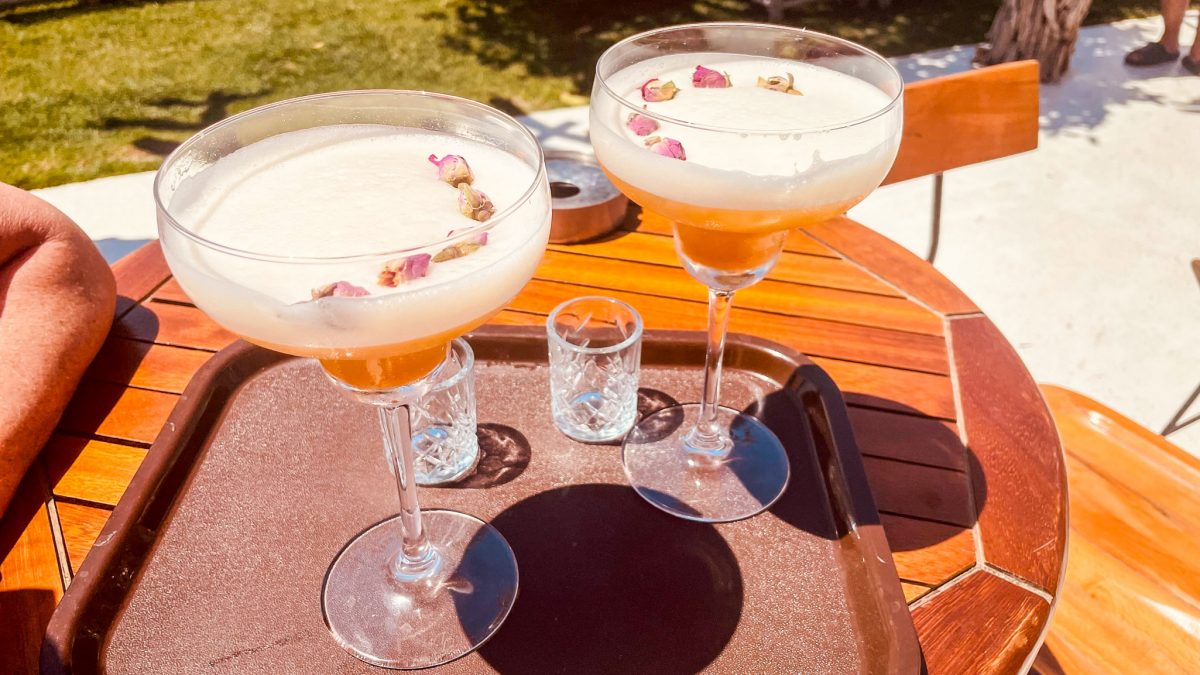 Two elegant cocktails garnished with dried rose buds on a wooden table at the Titanic Mardan Palace in Antalya