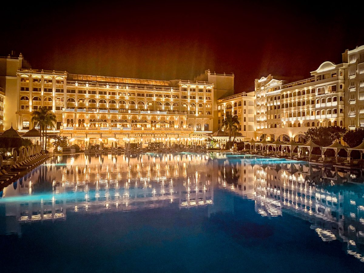 Night view of the Titanic Mardan Palace in Antalya with the illuminated hotel reflecting across the large swimming pool
