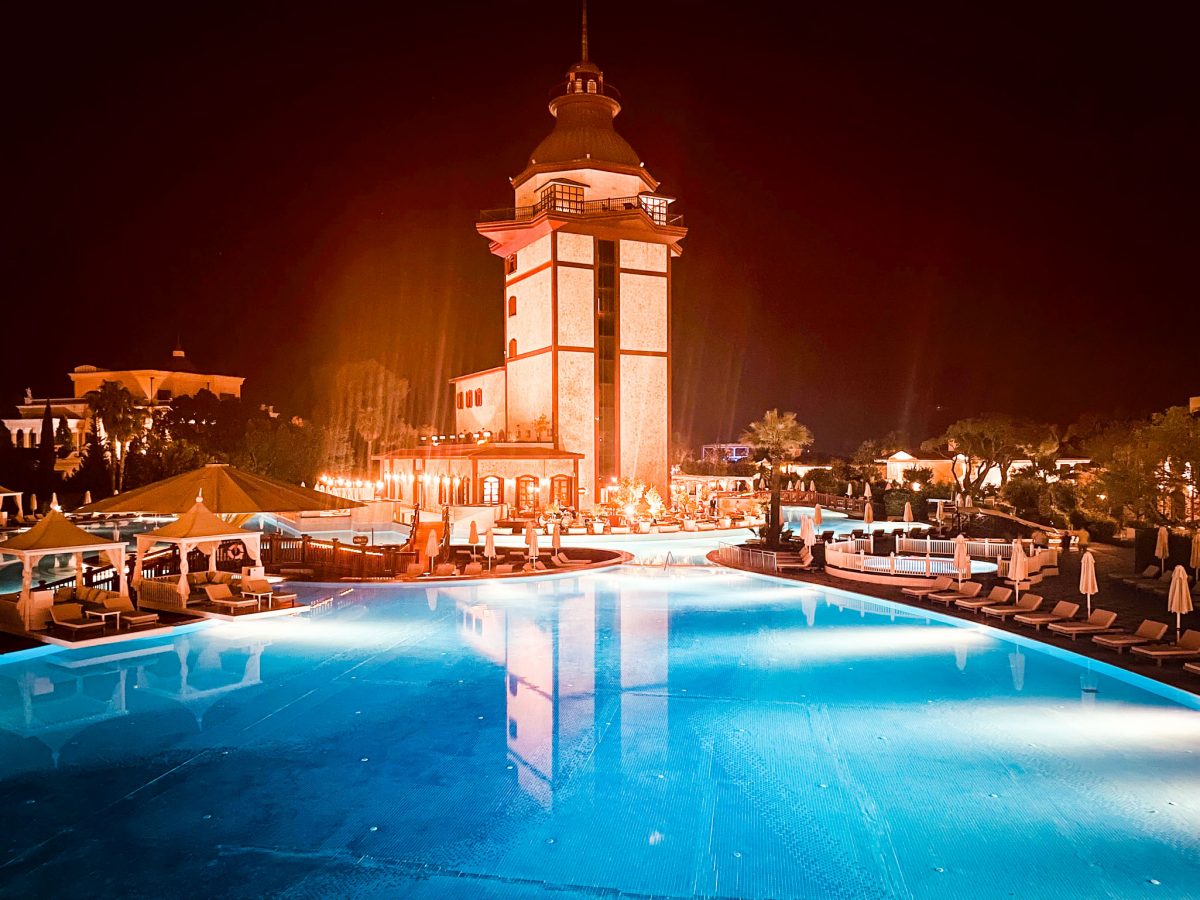 Night view of the illuminated lighthouse and pool area at the Titanic Mardan Palace in Antalya, Turkey