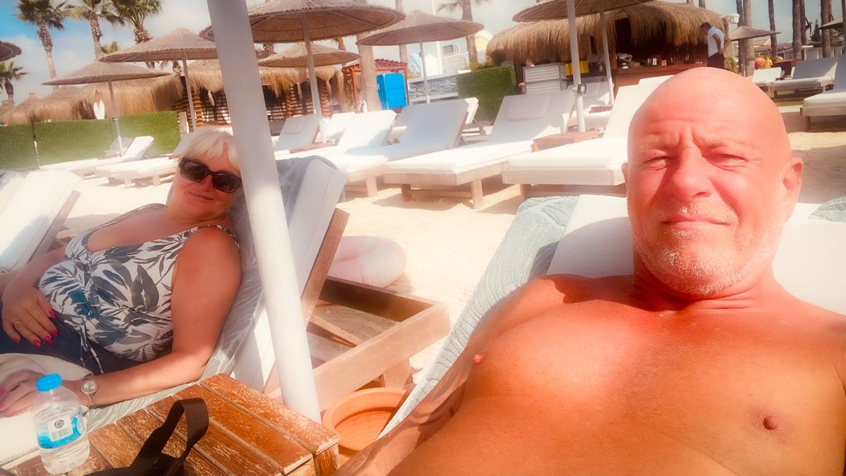 Two adults relaxing on sun loungers at a sunny beach with parasols at Titanic Mardan Palace
