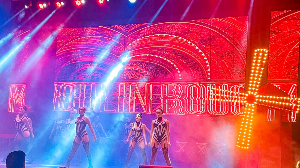 Dancers performing on a vibrant Moulin Rouge themed stage with red neon lights and a lit windmill at Titanic Mardan Palace in Antalya