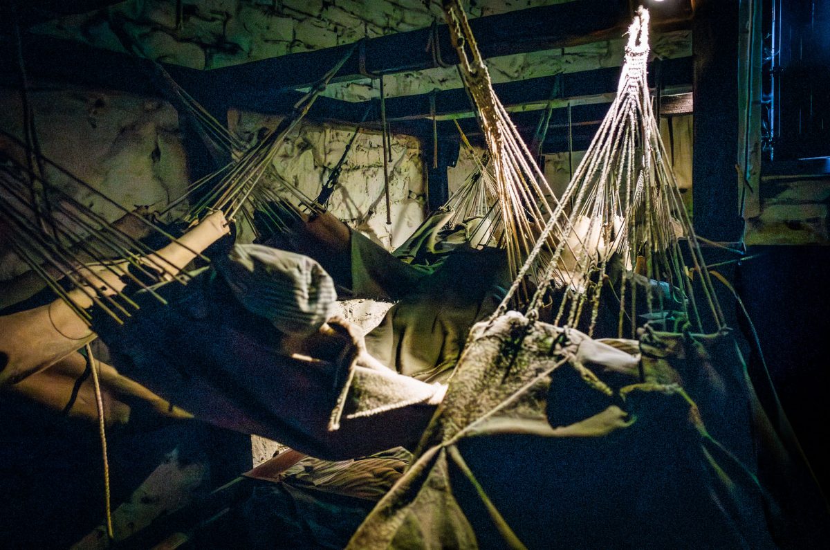 A close-up view of a prisoner of war mannequin sleeping in a tiered hammock, showing the cramped conditions in the Castle's former jail.