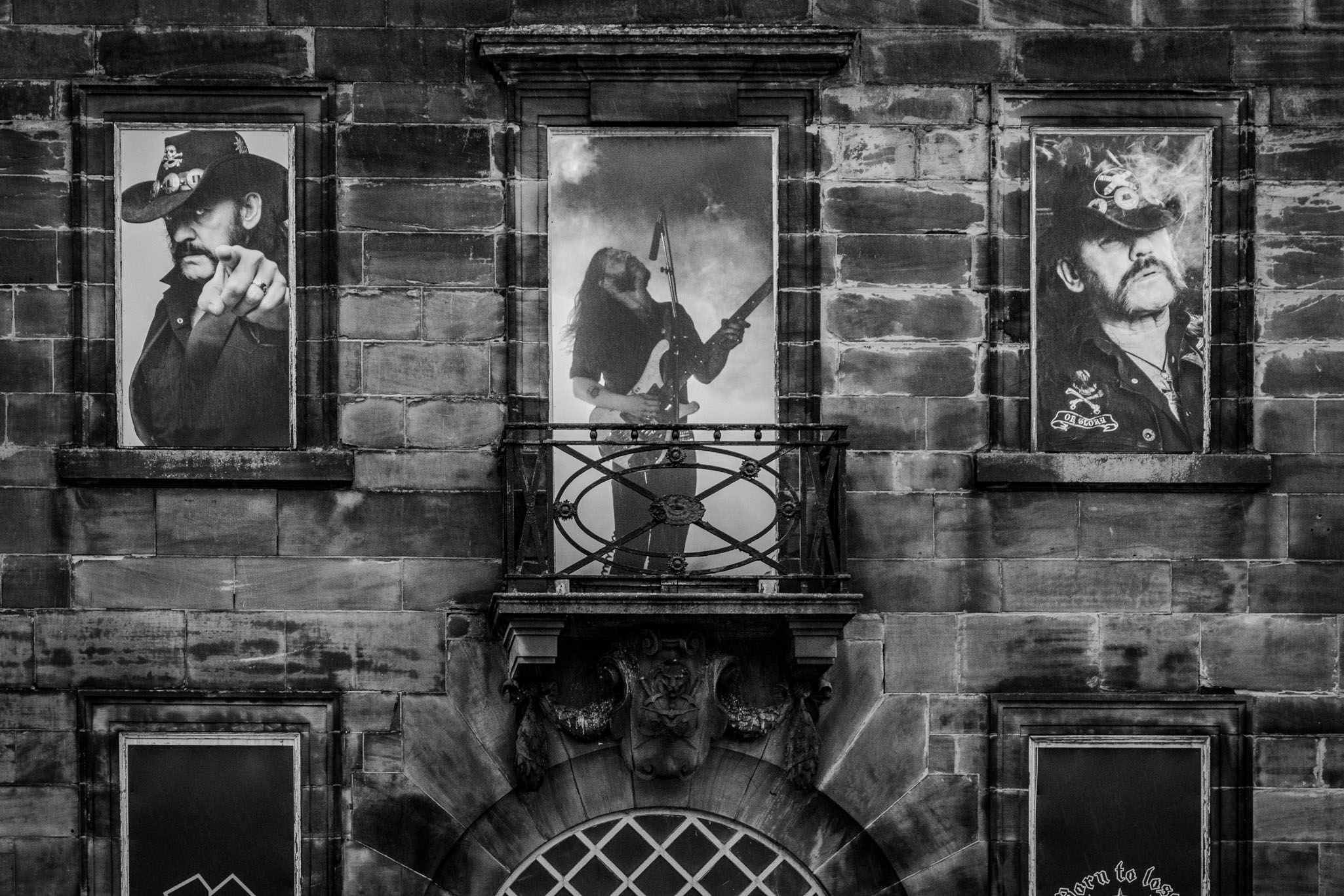 Detailed black and white photo of Lemmy Kilmister portraits on the windows surrounding a central balcony in Burslem.