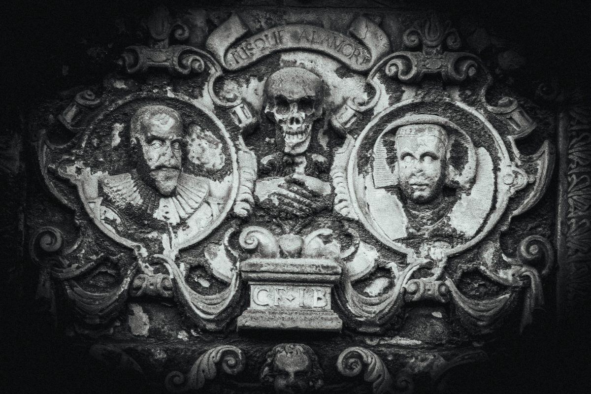 17th-century tombstone carving with skull, portraits, and memento mori.