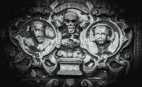 17th-century tombstone carving with skull, portraits, and memento mori.