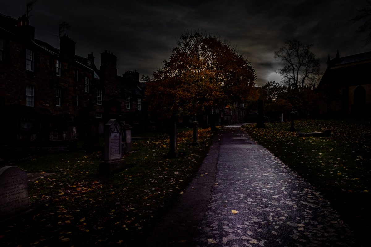 Dark, atmospheric path through Greyfriars Kirkyard at dusk with autumn leaves.