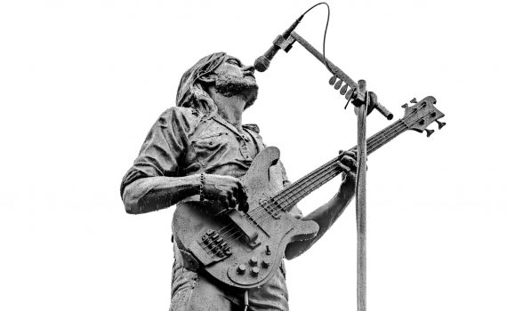 A dramatic, close-up, black and white shot of the Lemmy Kilmister statue playing bass and singing into the microphone.