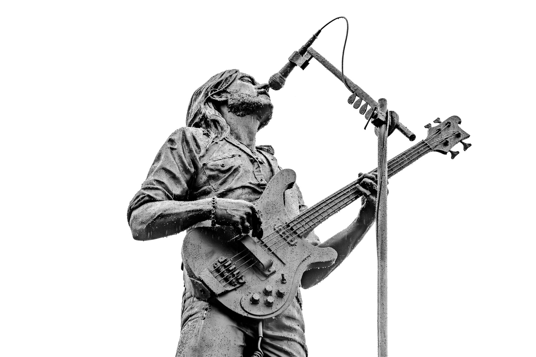 A dramatic, close-up, black and white shot of the Lemmy Kilmister statue playing bass and singing into the microphone.