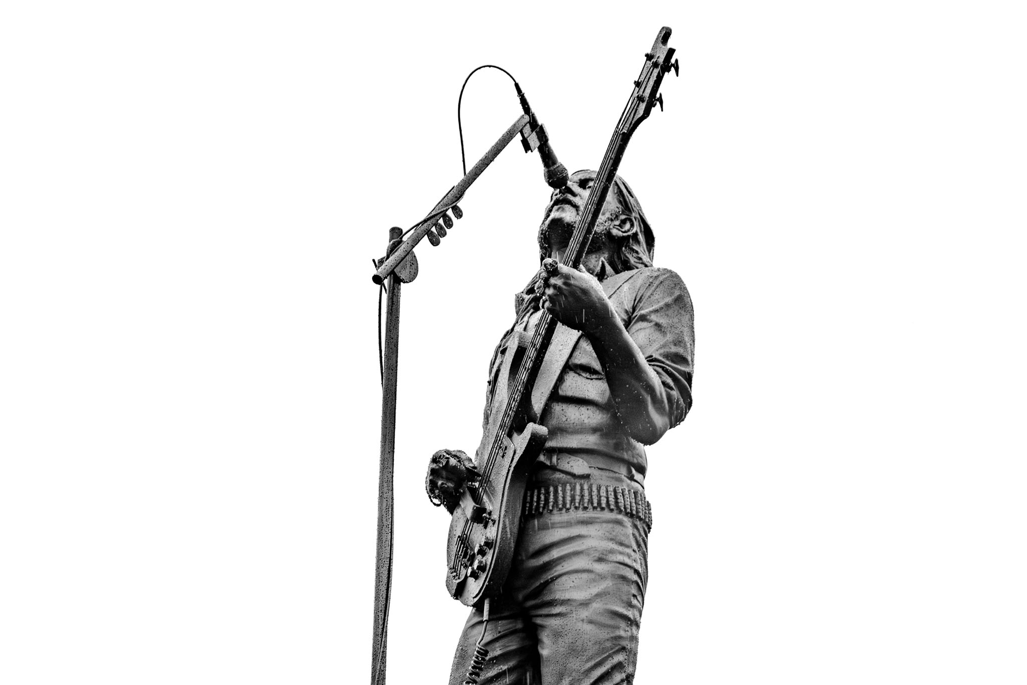 A close-up, low-angle, black and white profile of the Lemmy Kilmister statue singing into the microphone.