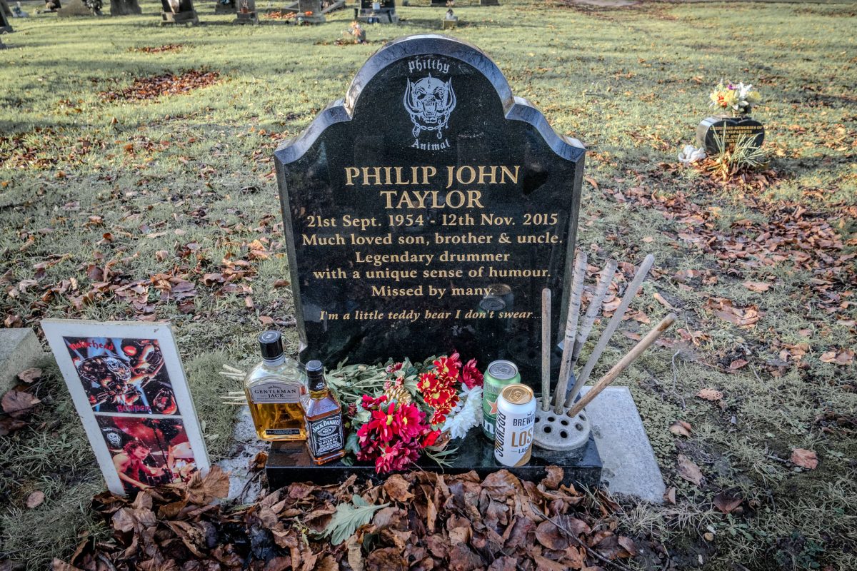 Full view of Phil Taylor's grave, showing the headstone, flowers, and Jack Daniel's.