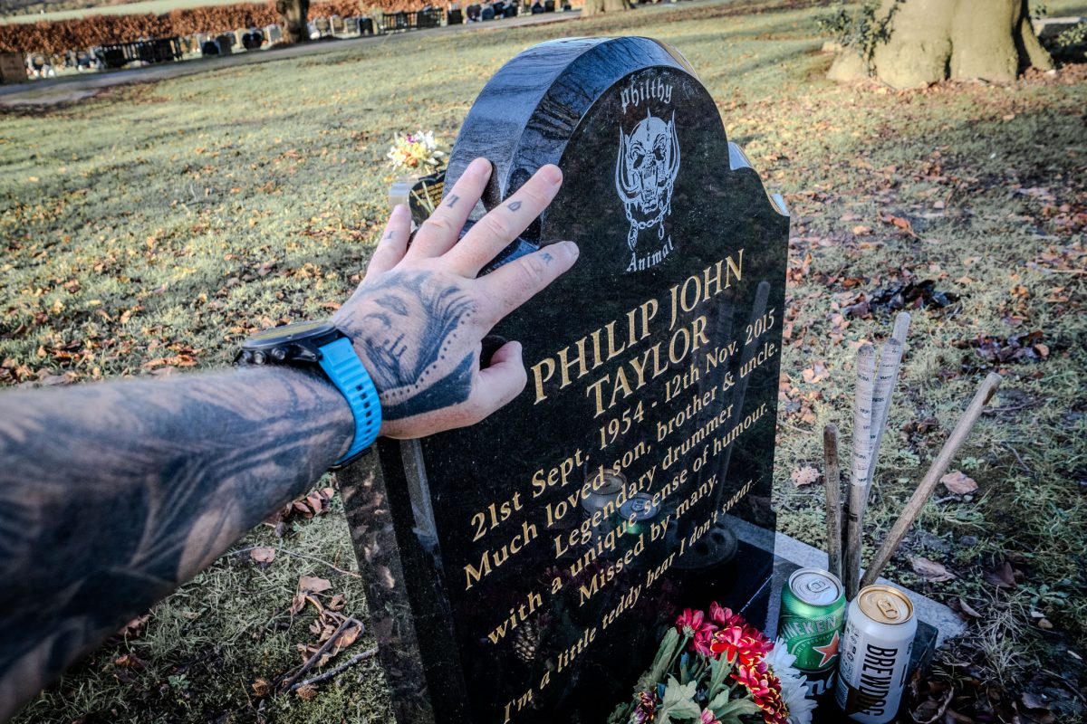 Tattoed hand touching Phil Taylor's headstone.