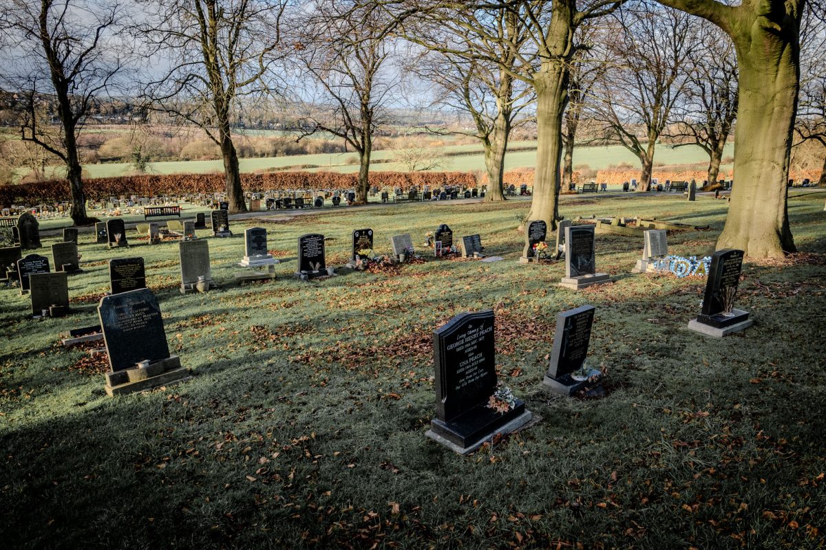 Wide shot of the cemetery with autumn trees and a view of the fields.