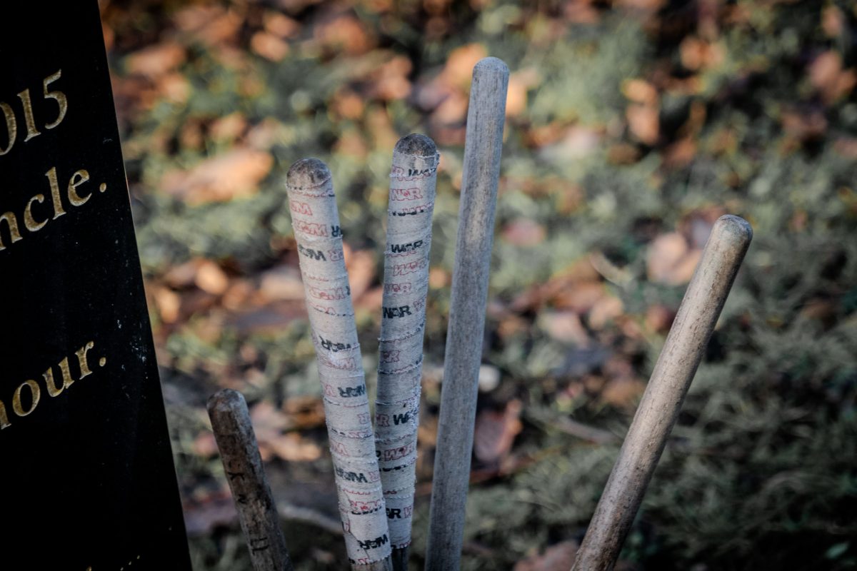 Close-up of wooden drumsticks wrapped with tape at the gravesite.