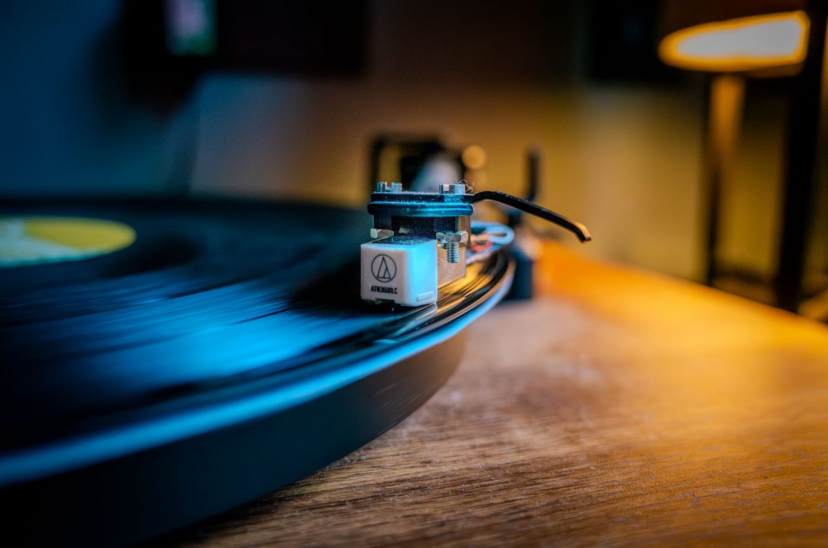 Close-up of an Audio-Technica turntable needle resting on a spinning black vinyl record.