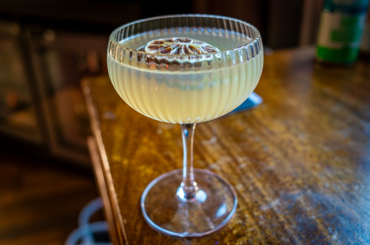 A chilled cocktail in a ribbed coupe glass topped with a dried citrus wheel garnish.