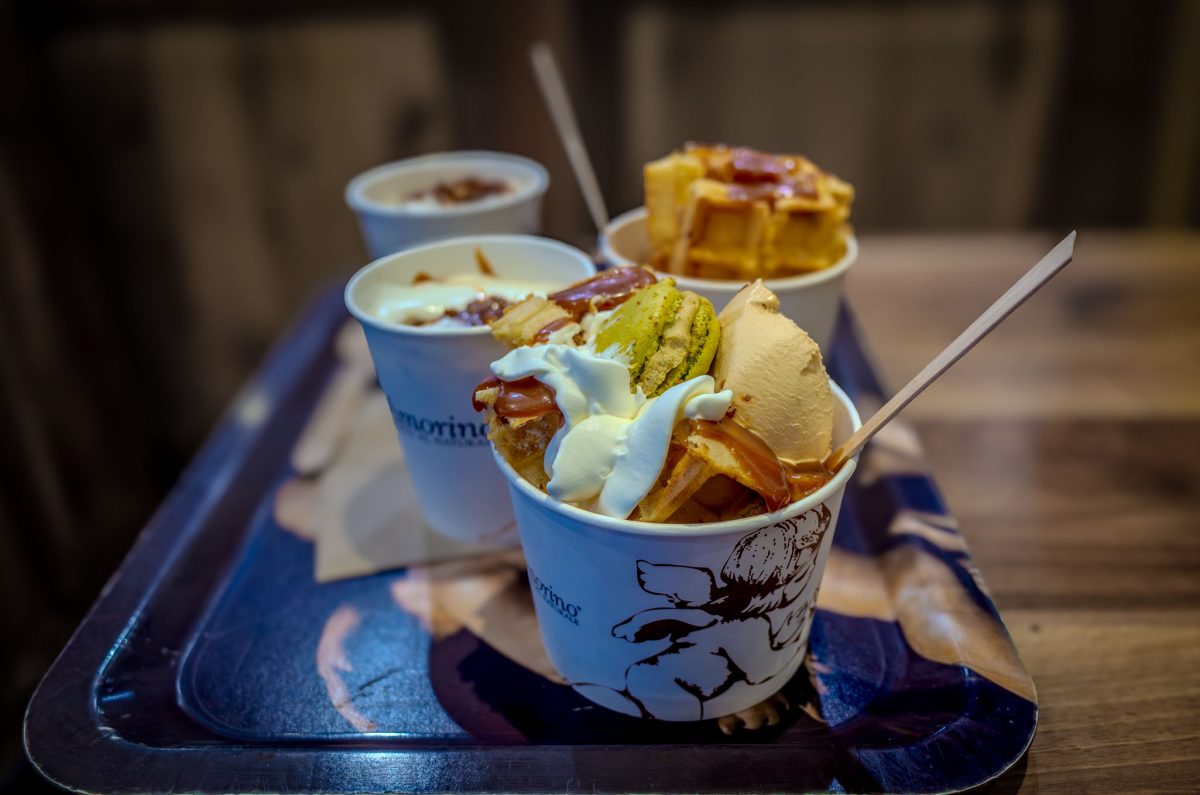 Cups of Amorino gelato topped with waffles, whipped cream, and a macaron.