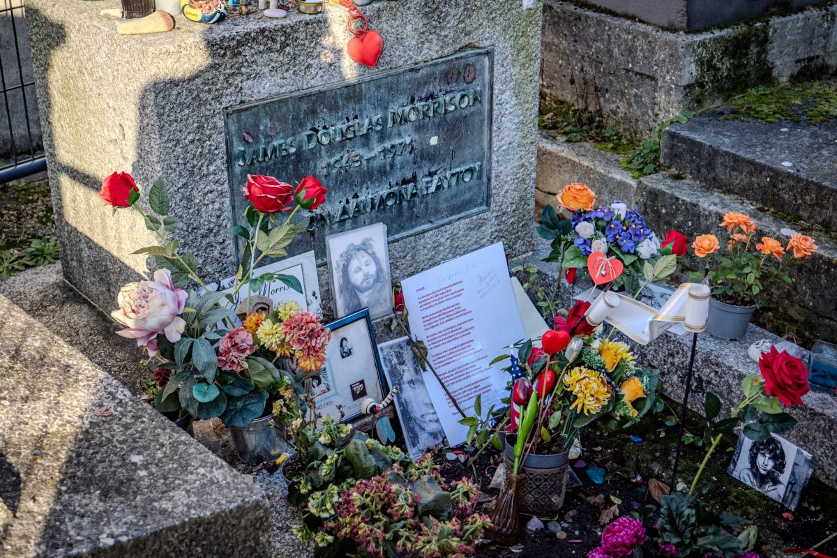 Close-up of the bronze plaque on Jim Morrison's grave inscribed with "James Douglas Morrison 1943-1971" and Greek text.