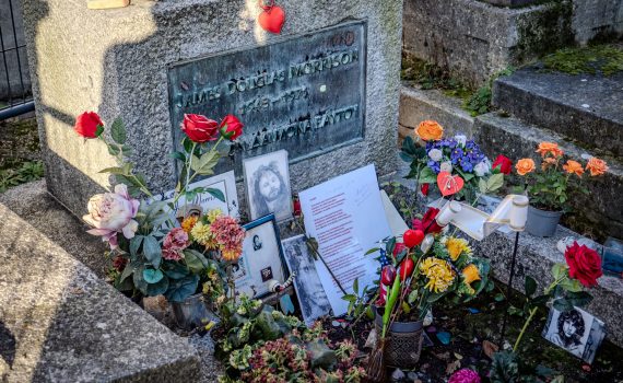 Close-up of the bronze plaque on Jim Morrison's grave inscribed with "James Douglas Morrison 1943-1971" and Greek text.