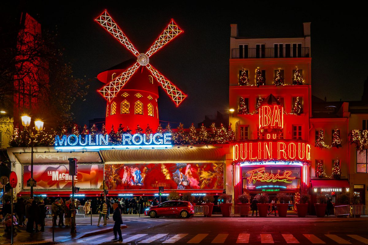 The neon red windmill and facade of the Moulin Rouge cabaret in Montmartre.