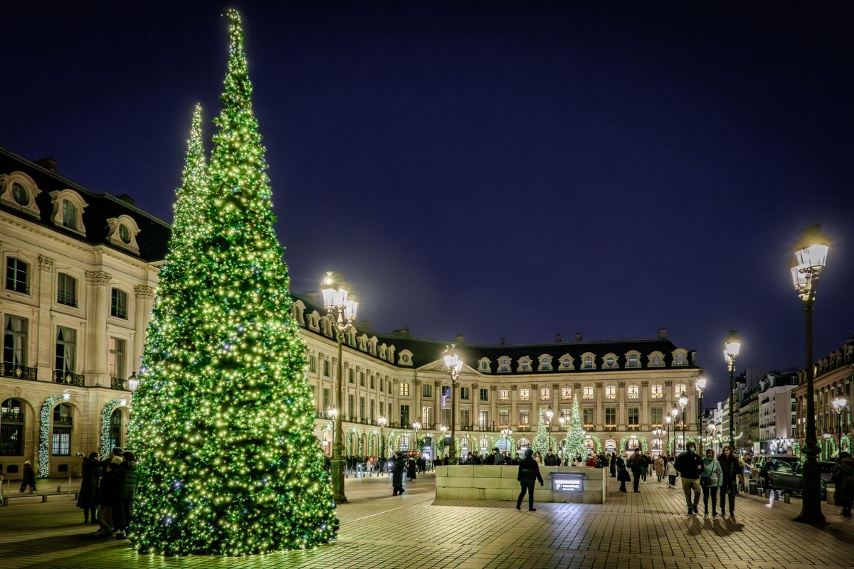 Large illuminated green Christmas trees in the center of Place Vendôme at night.