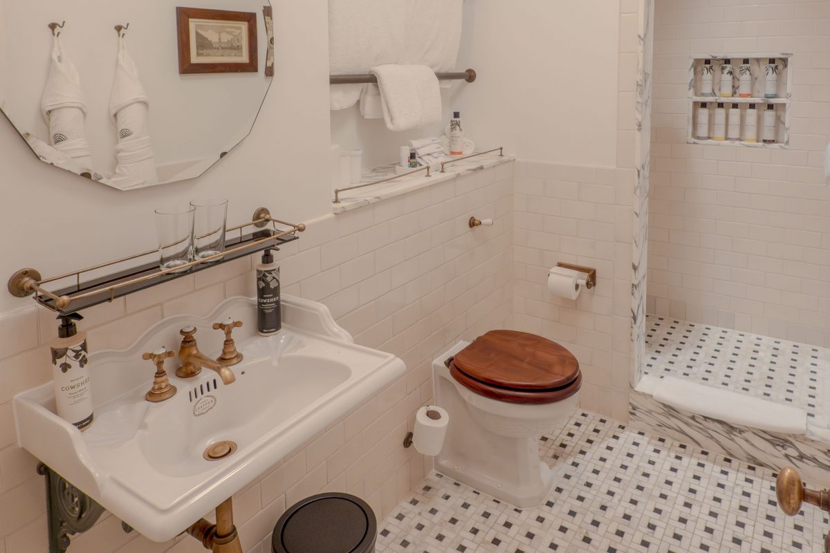 A bright bathroom with white subway tiles, a marble sink, and Cowshed products.